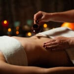 femme qui verse de l'huile de massage tantrique