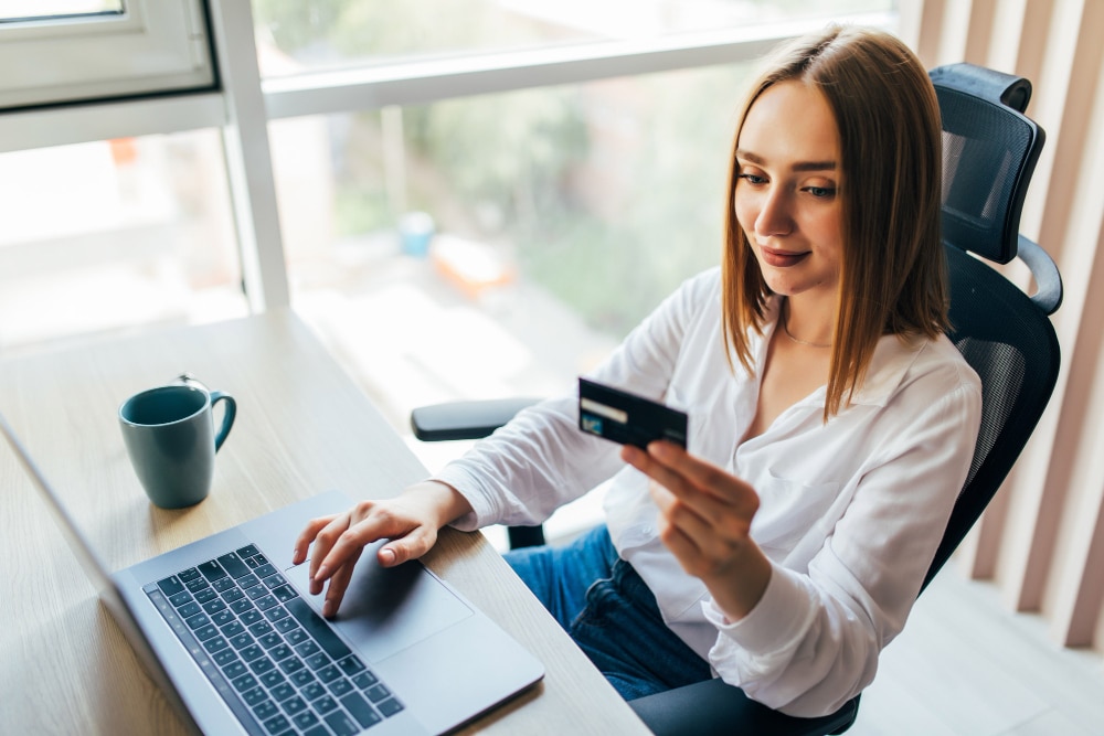 Femme réalisant un paiement en ligne avec sa carte bancaire