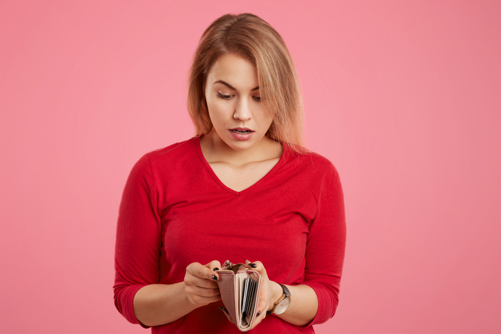 femme qui regarde dan son portefeuille et n'a plus d'argent